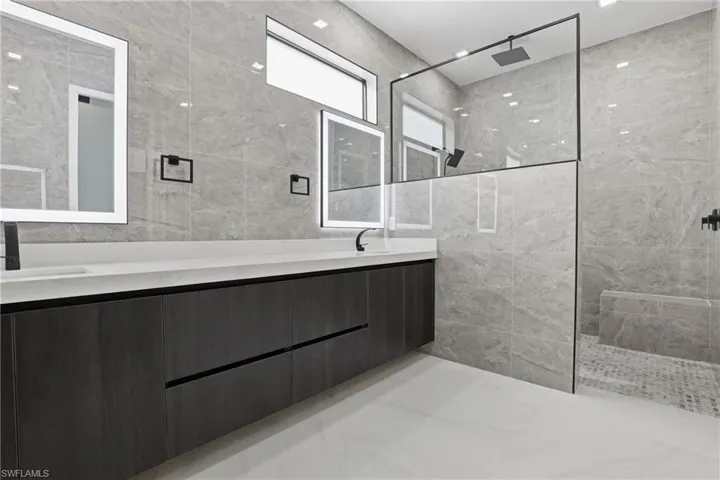 Spacious bathroom featuring a dual vanity with a light-colored countertop and wood-finish cabinetry