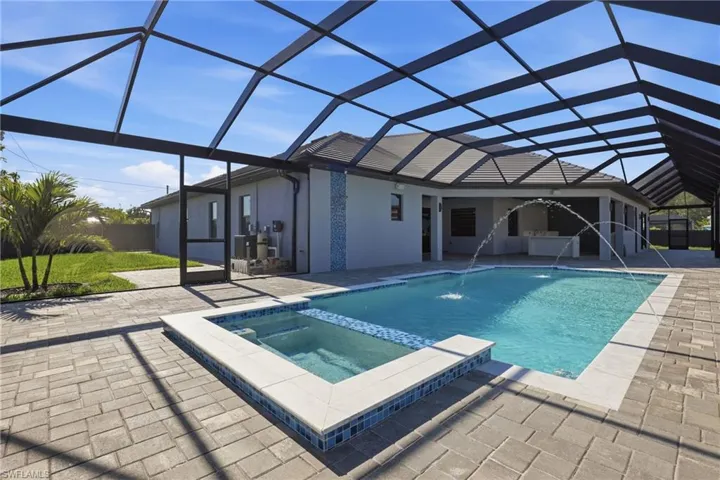 Expansive screened lanai featuring a swimming pool with integrated spa and water features