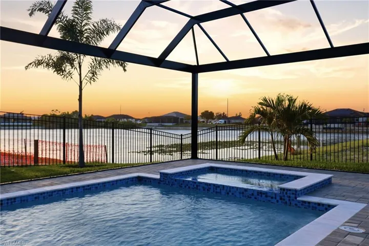 Screened lanai featuring a swimming pool, integrated spa with mosaic tile accents, and a paver deck