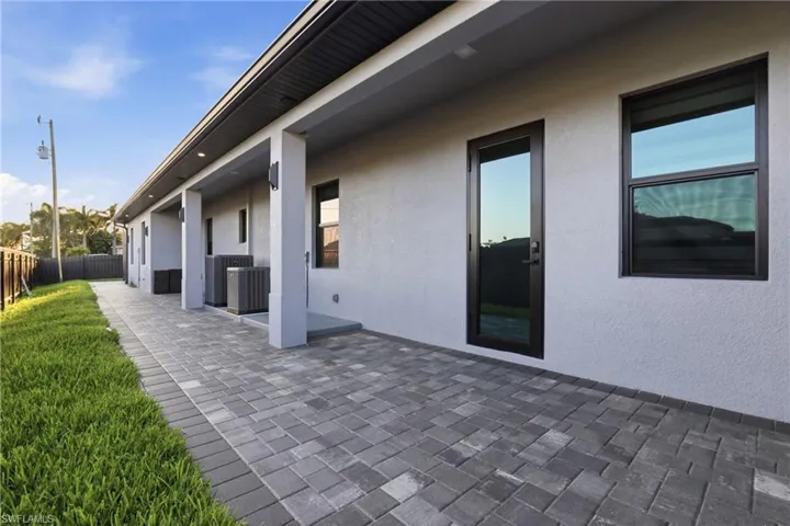 Expansive paver patio with a stucco exterior and black-framed windows