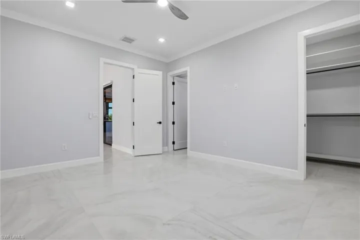Spacious interior room featuring large format tile flooring, crown molding, recessed lighting, and a ceiling fan