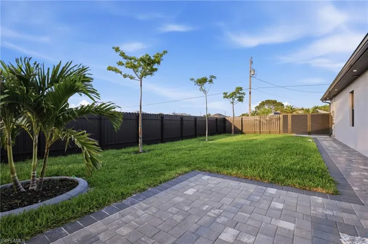 Expansive backyard featuring a paver patio with a dark border, a manicured lawn, and a privacy fence
