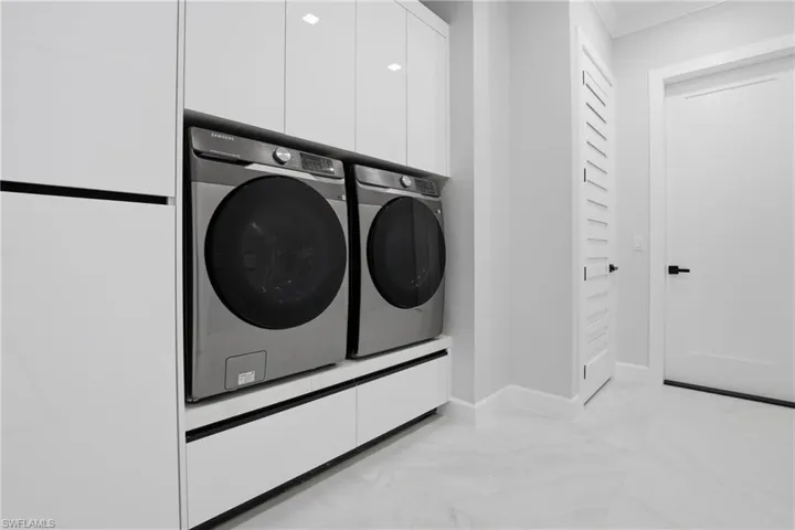 Laundry area featuring integrated appliances, white high-gloss cabinetry, and a solid-surface countertop