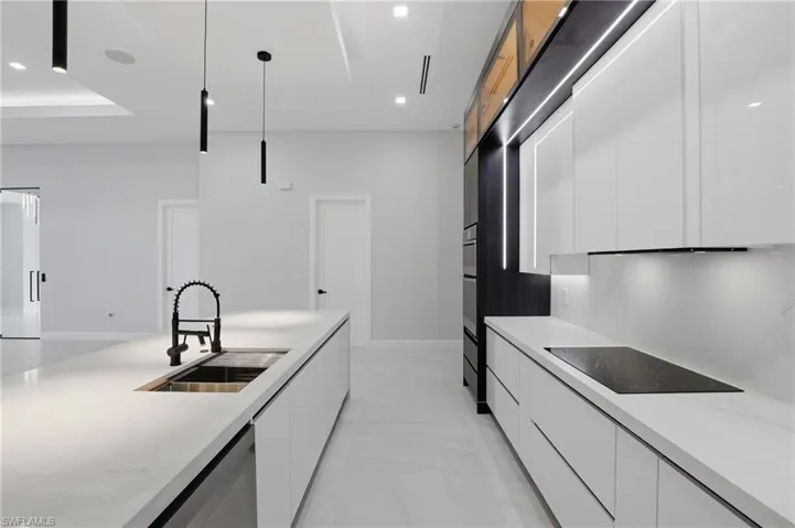 Sleek contemporary kitchen featuring a large island with an integrated sink and black faucet