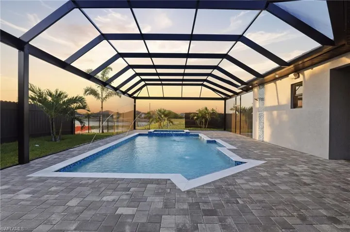Screened pool enclosure featuring a rectangular pool with integrated water features, blue mosaic tile accents, and paver decking