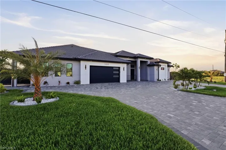 Modern exterior featuring a dark tile roof, smooth gray stucco siding, and a black garage door with frosted glass panels