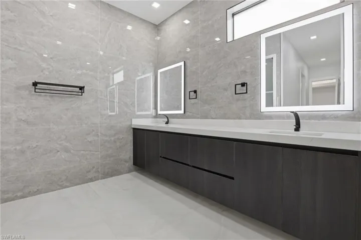 Modern bathroom featuring a double vanity with dark wood-finish cabinetry, white countertops, and integrated rectangular sinks