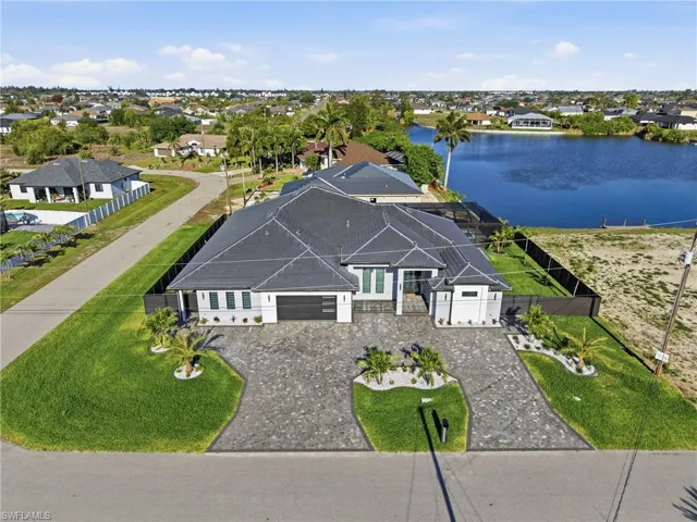 Modern residence featuring a dark gray tile roof and a paver driveway