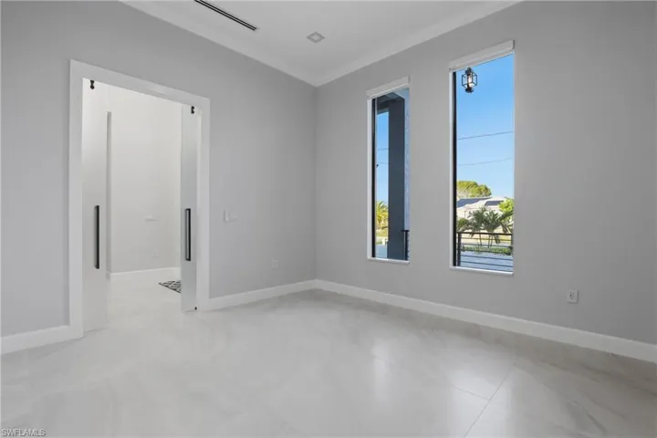 Bright interior space featuring two tall windows, light-colored tile flooring, and a modern barn door entry