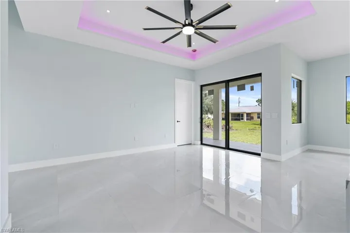 Kitchen featuring white cabinetry, light tile patterned floors, pendant lighting, a raised ceiling, and a center island with sink