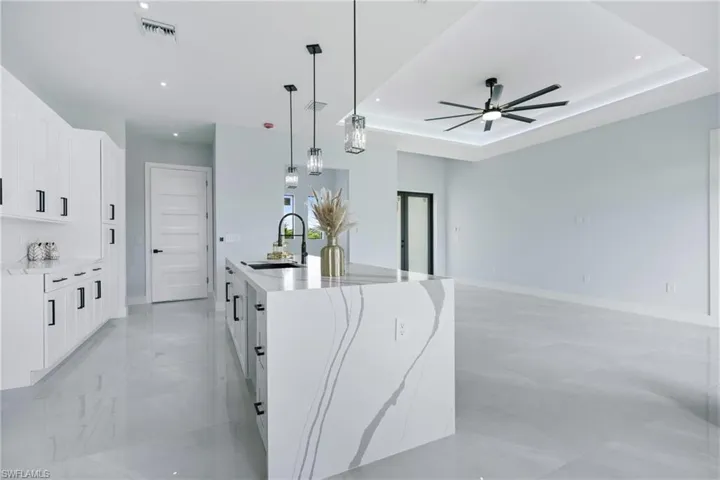 Kitchen with sink, a tray ceiling, a center island with sink, and light tile patterned floors