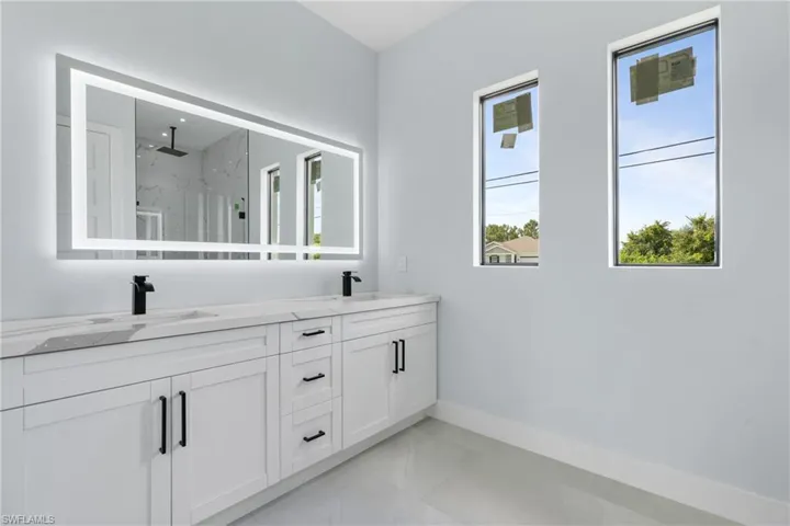 Bathroom featuring dual vanity, tile patterned flooring, and a healthy amount of sunlight
