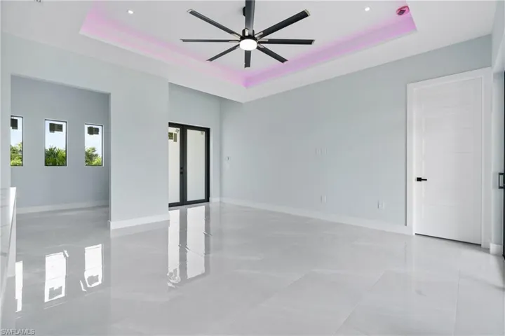 Unfurnished room featuring ceiling fan, light tile patterned floors, and a tray ceiling