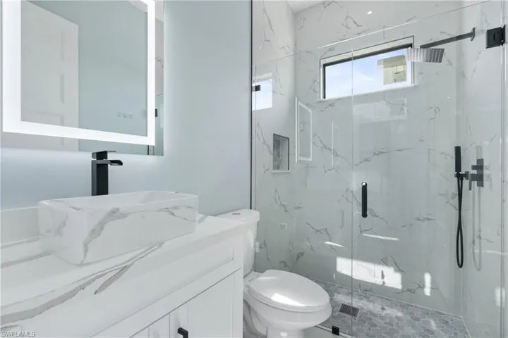 Bathroom featuring a shower with shower door, vanity, and toilet