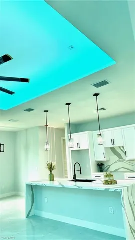 Kitchen featuring hanging light fixtures, sink, and white cabinets