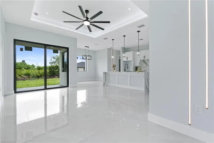 Unfurnished room featuring sink, light tile patterned flooring, ceiling fan, and a tray ceiling