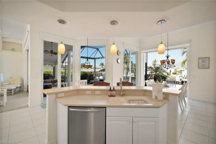 Kitchen with pendant lighting, sink, light tile patterned floors, dishwasher, and white cabinetry