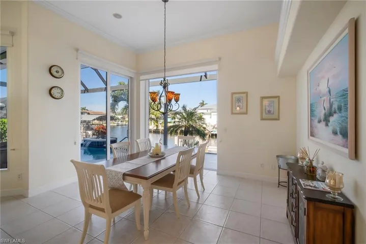 Tiled dining space with ornamental molding, a water view, and an inviting chandelier