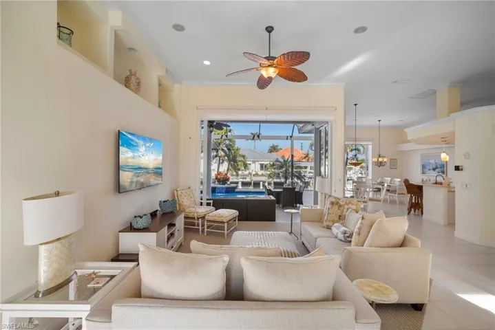 Tiled living room featuring ornamental molding and ceiling fan with notable chandelier