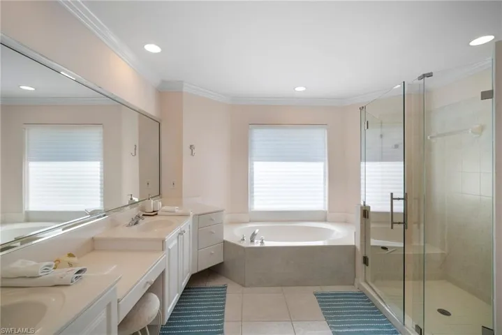 Bathroom with tile patterned flooring, vanity, ornamental molding, and plus walk in shower