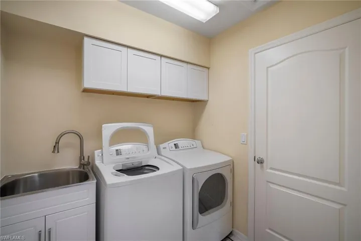 Clothes washing area with cabinets, separate washer and dryer, and sink