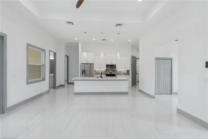 Kitchen with appliances with stainless steel finishes, pendant lighting, a kitchen island with sink, and light tile patterned floors