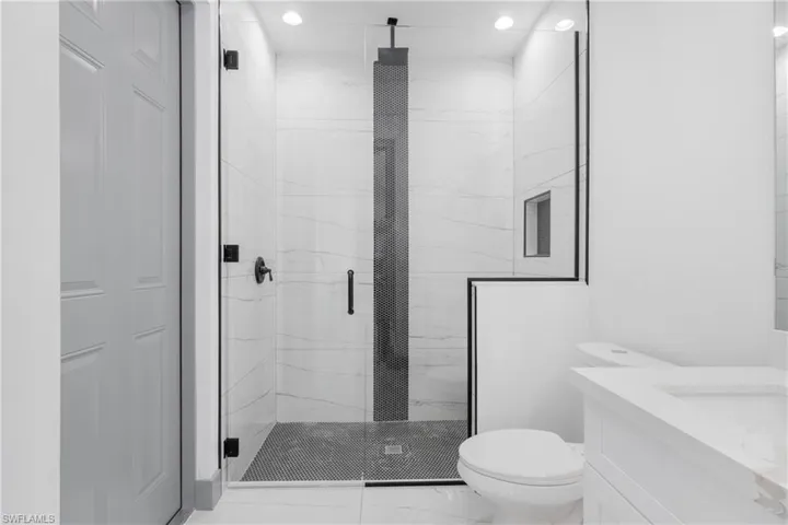 Bathroom with vanity, an enclosed shower, and toilet