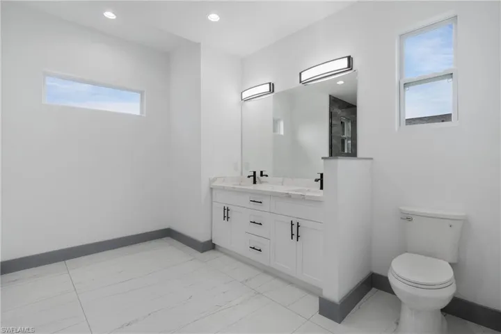 Bathroom with tile patterned flooring, double vanity, and toilet