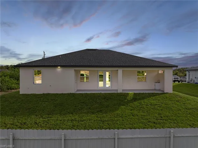 Property exterior at dusk featuring a patio area and a lawn
