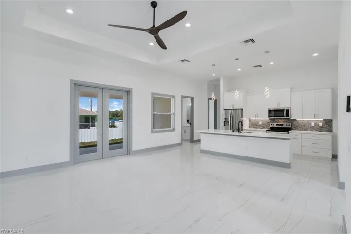 Kitchen with a kitchen island with sink, a raised ceiling, appliances with stainless steel finishes, and light tile patterned floors