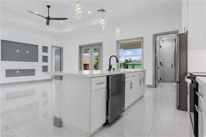 Kitchen featuring hanging light fixtures, white cabinets, sink, a center island with sink, and light tile patterned floors