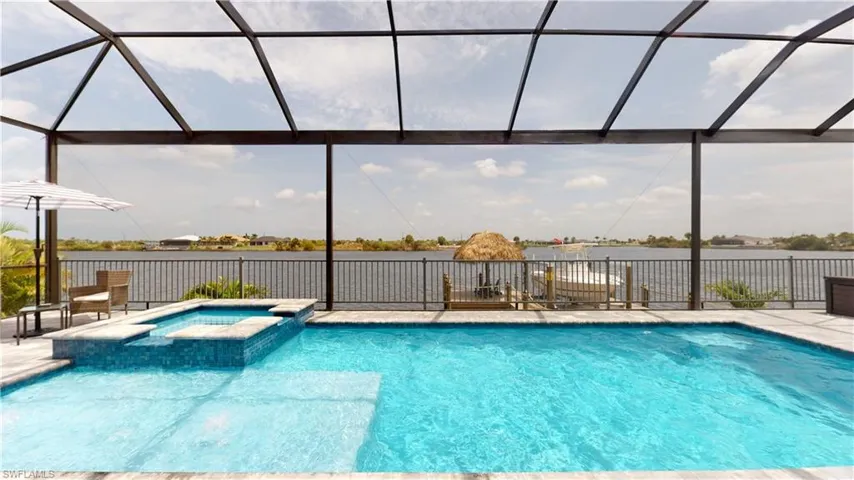 View of swimming pool featuring a water view, a pool with connected hot tub, and a patio area
