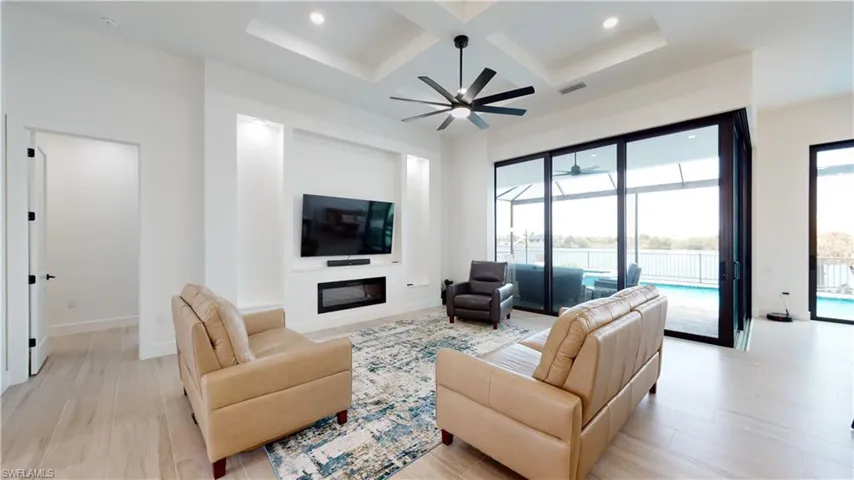 Living room featuring coffered ceiling, a ceiling fan, recessed lighting, beam ceiling, and a glass covered fireplace
