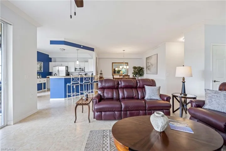 Living area featuring ornamental molding, a chandelier, ceiling fan, and baseboards