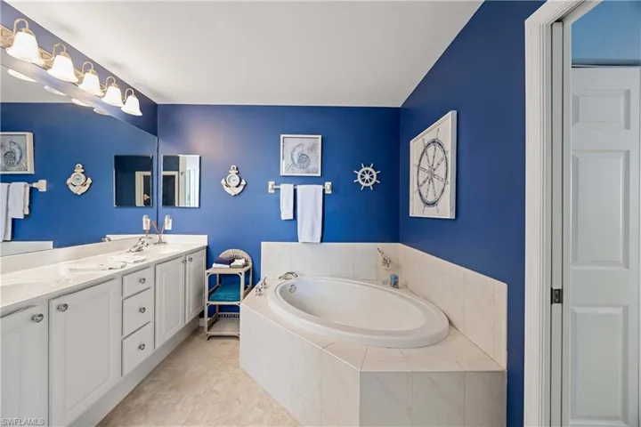 Bathroom featuring a garden tub, double vanity, and tile patterned floors
