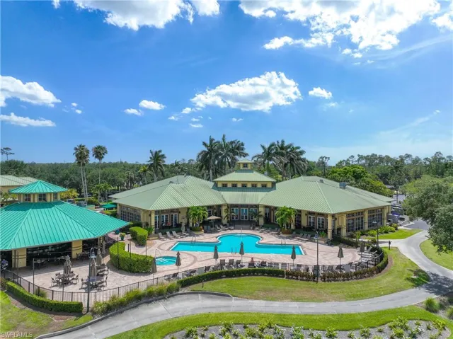 Community pool with fence, view of scattered trees, and a patio