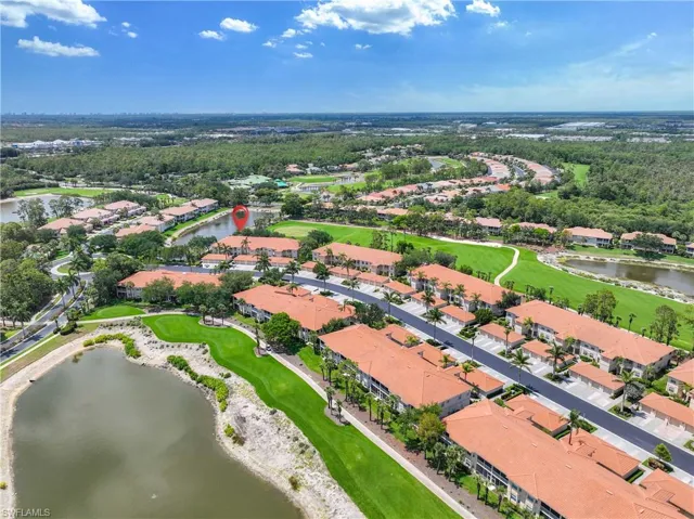 Aerial view of property and surrounding area featuring a large body of water, a golf course, and nearby suburban area