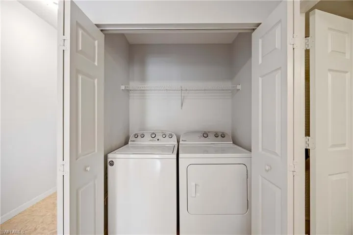 Washroom featuring washer and clothes dryer, light tile patterned flooring, and baseboards