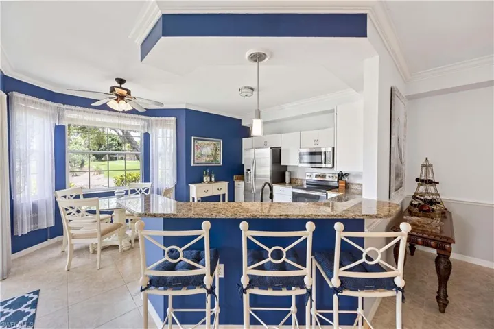 Kitchen featuring stainless steel appliances, white cabinetry, ceiling fan, crown molding, and baseboards