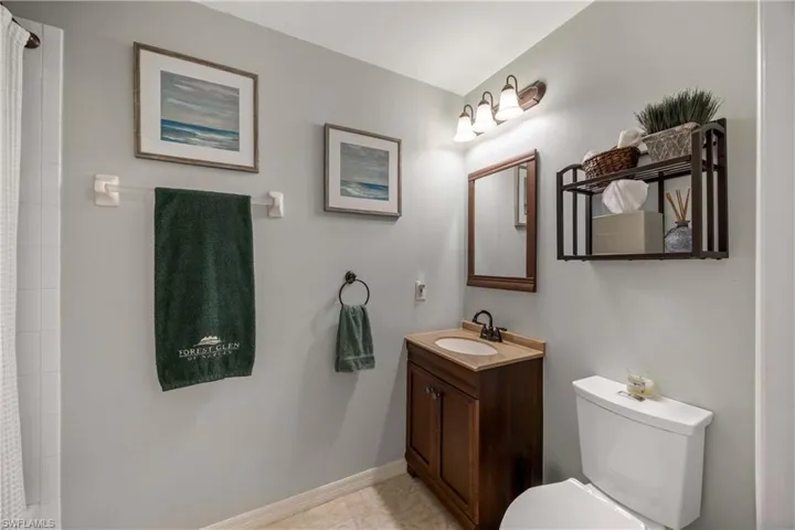 Bathroom featuring toilet, vanity, baseboards, curtained shower, and tile patterned floors