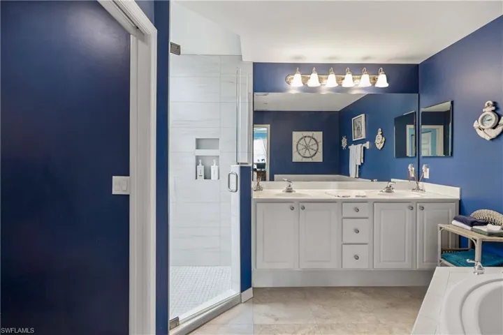 Full bath featuring a shower stall, double vanity, and a bath