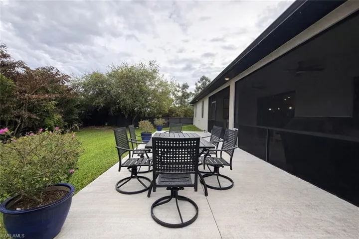 Fenced backyard featuring outdoor dining area, a patio area, a sunroom, and a ceiling fan
