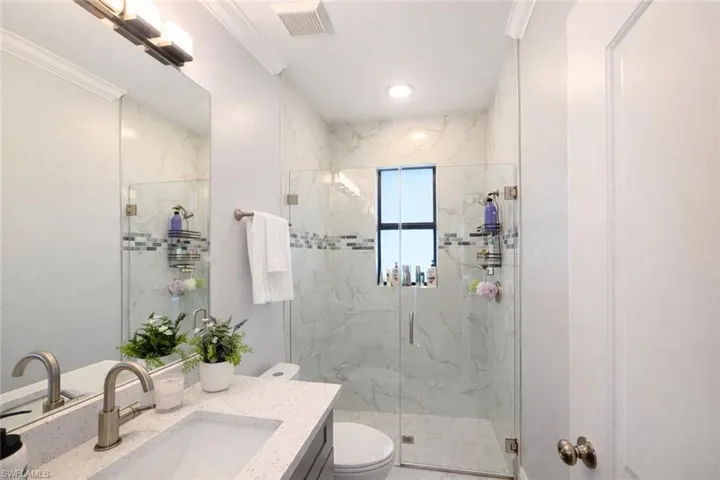 Full bathroom featuring ornamental molding, vanity, and a marble finish shower