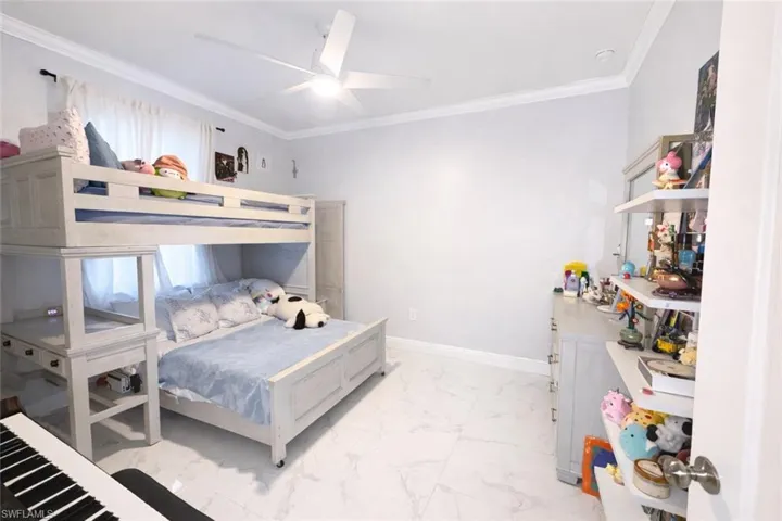 Bedroom featuring ornamental molding, light marble finish floors, and a ceiling fan
