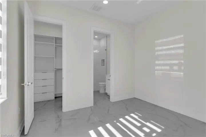 Unfurnished bedroom featuring connected bathroom, a walk in closet, and a closet