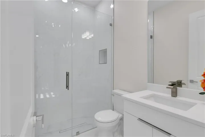 Bathroom with vanity, toilet, and a shower with shower door