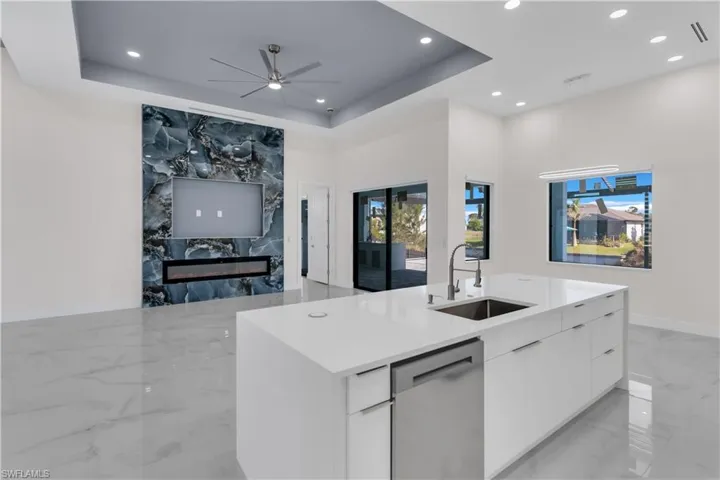 Kitchen featuring white cabinetry, a kitchen island with sink, stainless steel dishwasher, and sink