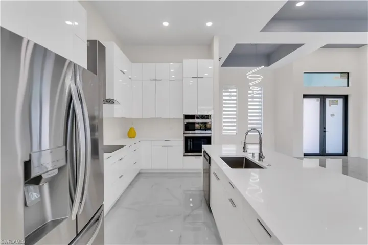Kitchen featuring white cabinetry, french doors, sink, decorative light fixtures, and appliances with stainless steel finishes