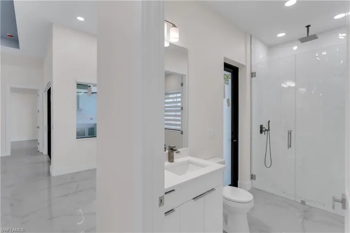 Bathroom featuring vanity, toilet, and an enclosed shower