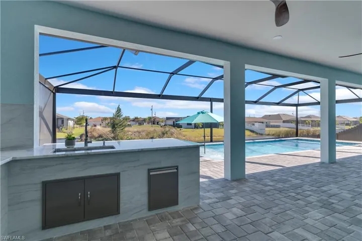 View of pool with a patio, ceiling fan, a lanai, and a wet bar